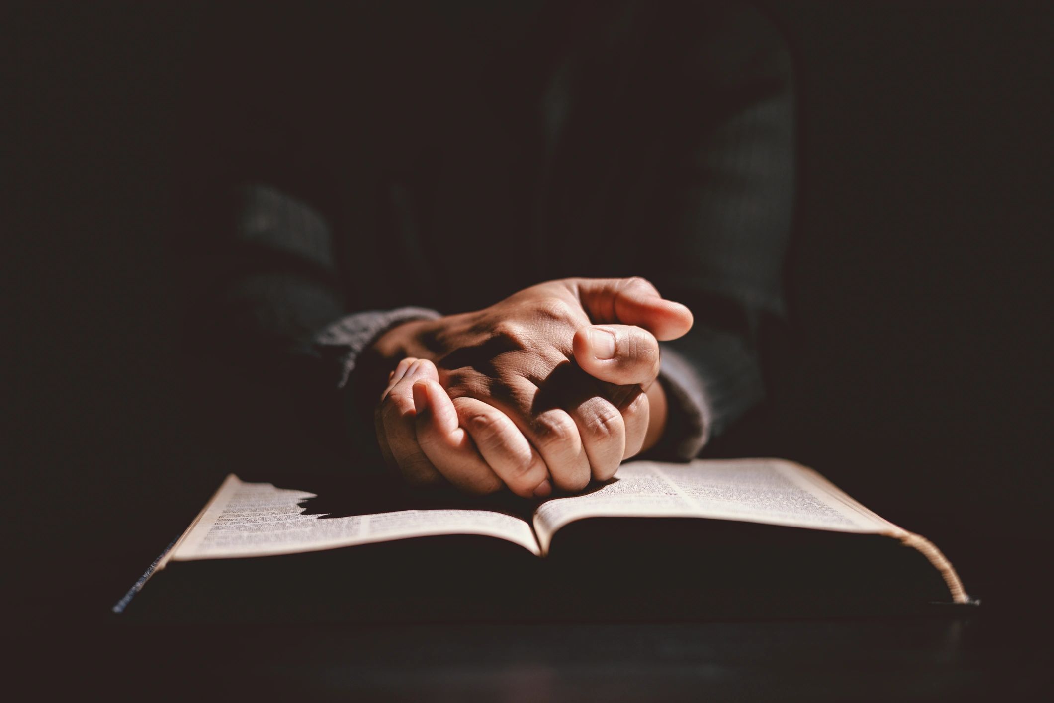 Hands folded in prayer on a Bible