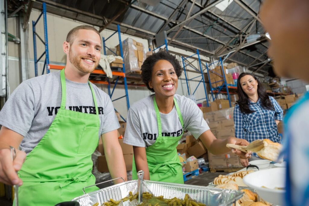 Volunteers serving hot meal to people in community soup kitchen